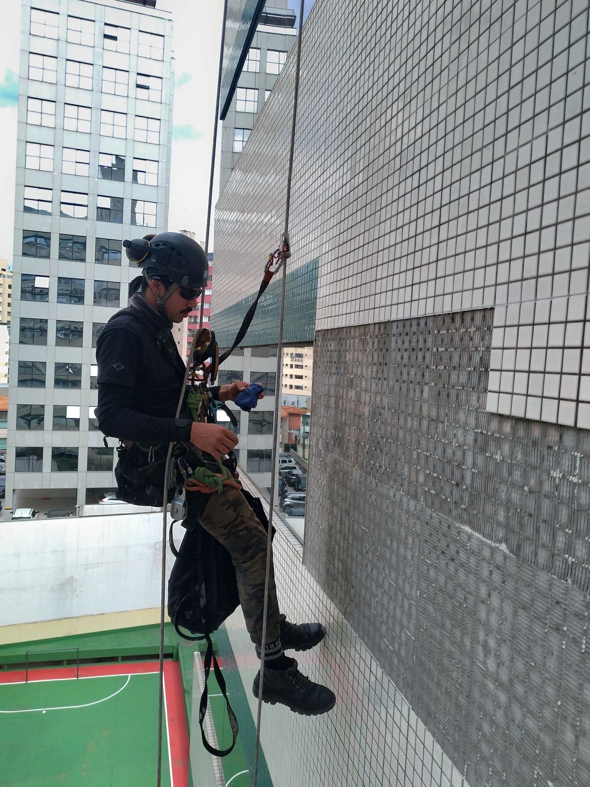 Profissional suspenso examinando de perto o revestimento da fachada de um edifício
